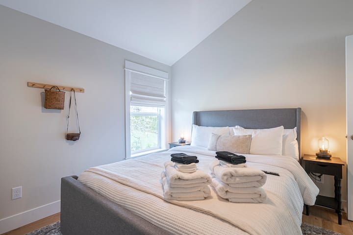 Upstairs room with a comfortable queen bed, offering a cozy and inviting atmosphere. The room features natural light, tasteful decor, and a peaceful setting for a restful stay.