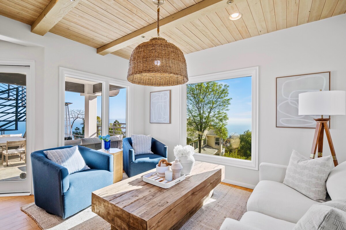 Ontspan in 'Woonkamer 2' van The Malibu Cloud House, met een licht gevuld interieur met hoge plafonds en stijlvolle, comfortabele stoelen. Ga naar het aangrenzende 'Balkon 1' voor een panoramisch uitzicht op de oceaan en een verademing.