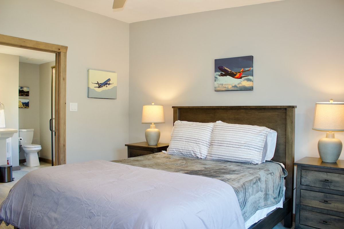 The third level of the home features 3 traditional bedrooms. Pictured here is a queen bedroom decorated with aviation memorabilia with an attached full bath. 