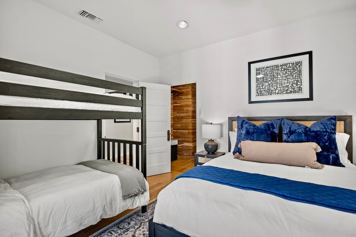 חדר שינה למעלה בבית הראשי עם מיטה מלאה ומיטת קומתיים, טלוויזיה וחדר רחצה צמוד