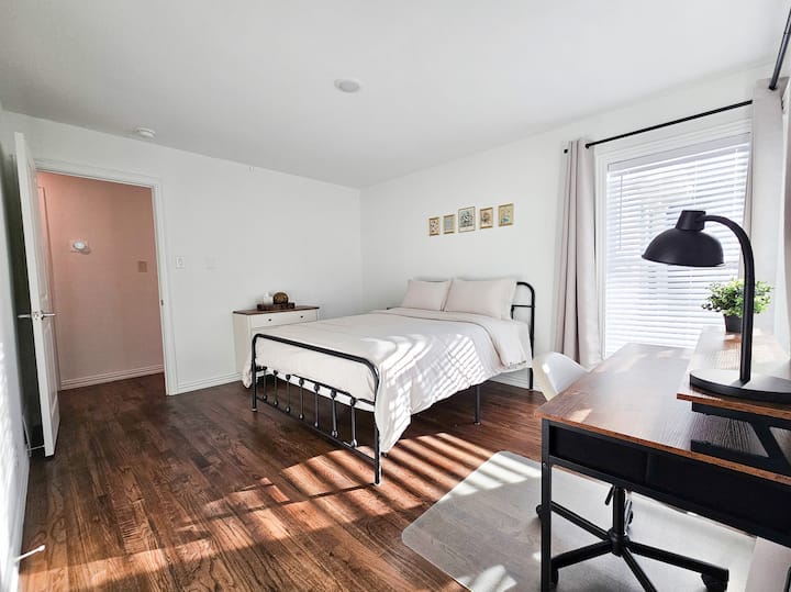 Dormitorio con cama tamaño queen size y espacio de trabajo dedicado.