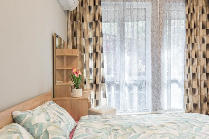 Chumba cha kulala cha kimtindo kilicho na mapambo ya mbao yenye joto, kabati jeupe lenye vifaa vya mbao na meza ya kifahari ya kuvaa. Sehemu hiyo inaangazia utulivu na utulivu, bora kwa ajili ya mapumziko kamili na starehe.