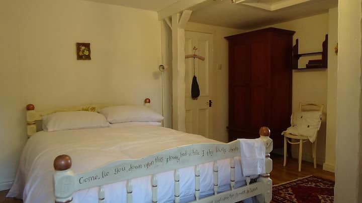 Arriba, este cómodo dormitorio está amueblado en un estilo de casa de campo tradicional con muebles únicos pintados a mano. El baño privado y el lavabo se suman a la comodidad de esta encantadora habitación.