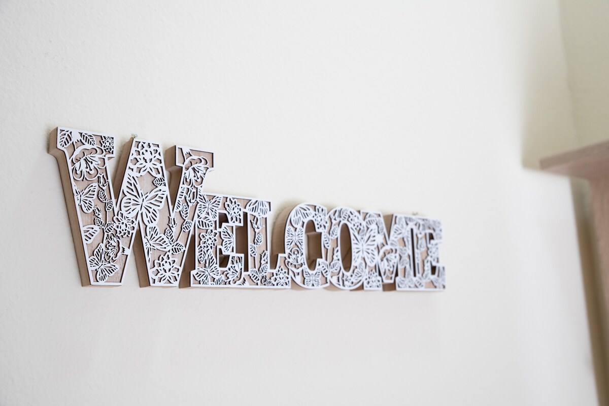 A decorative 'WELCOME' sign is mounted on a light-colored wall. The sign features intricate floral patterns, adding a touch of artistry to the entryway.