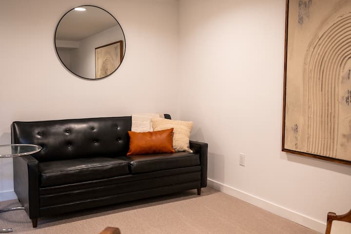 تحتوي غرفة المعيشة في الطابق السفلي على أريكة قابلة للسحب مع مرتبة كاملة الحجم. 