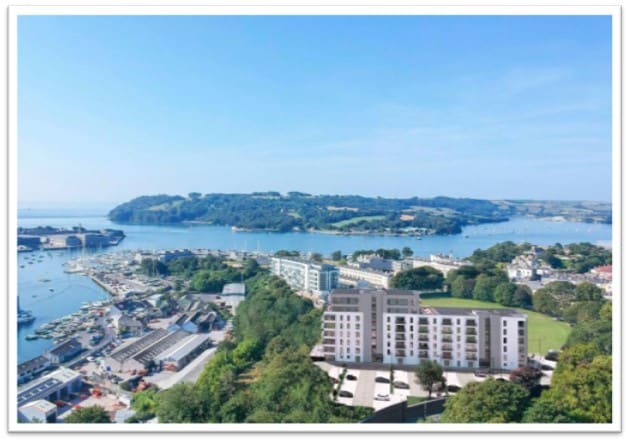 A scenic aerial view reveals the Mount Wise Estate situated near Plymouth's coastline, surrounded by lush greenery and water. The harbor is visible with various boats anchored, and hills form a backdrop under a clear blue sky, enhancing the serene environment.