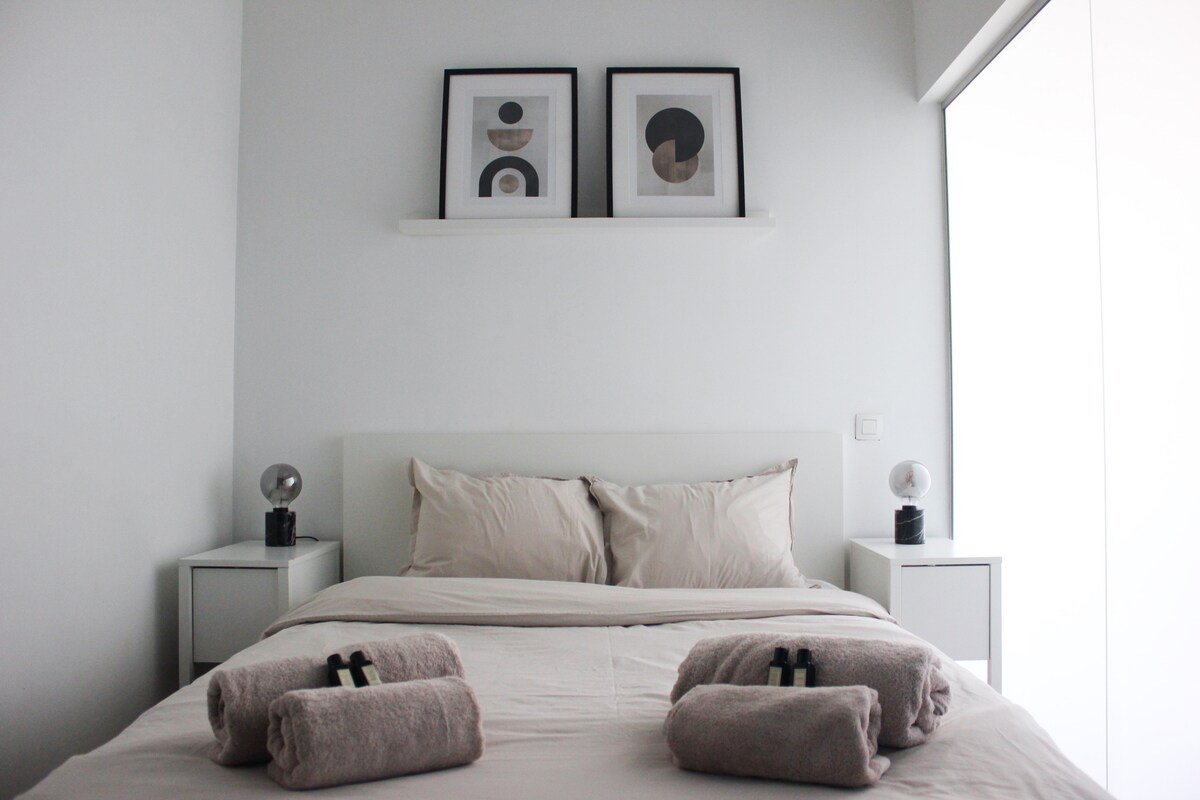 - غرفة نوم بسيطة مع لوحة ألوان نظيفة ومحايدة تحتوي على سرير مصنوع بعناية مع بياضات ومناشف باللون البيج الناعم
- الفن التجريدي يزين الجدار، مما يضيف لمسة خفية من الشخصية
- مساحة مشرقة ومهدئة مصممة للراحة والاسترخاء