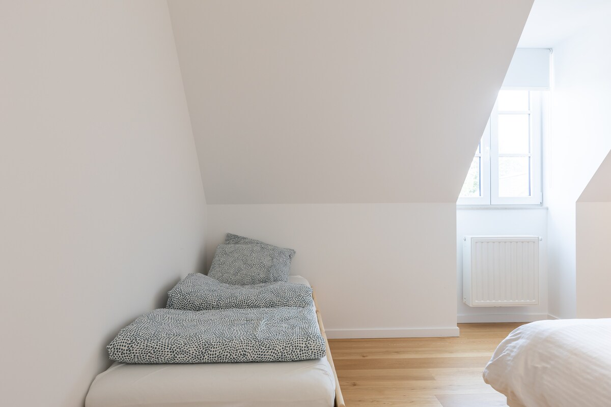 غرفة نوم كبيرة بسرير مزدوج وسرير بطابقين لطفلين وخزانة ملابس ومكتب وطاولتين بجانب السرير