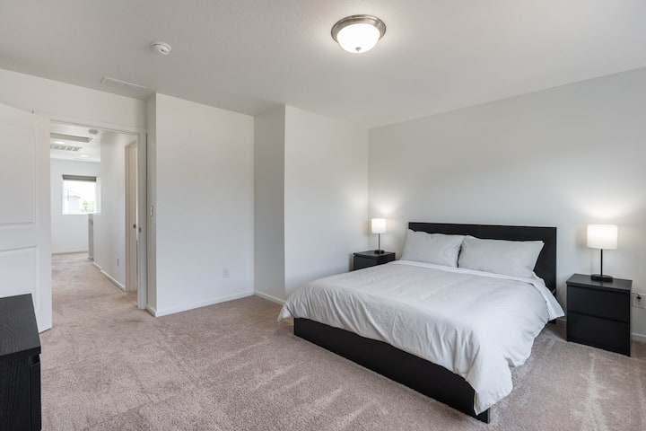 The master bedroom has a queen-size bed, two modern nightstands, and lamps with USB chargers.