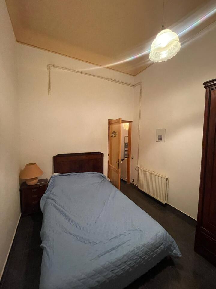 Spálňa s manželskou posteľou, nočným stolíkom, lampou, čelo postele, ventilátorom a šatníkom.