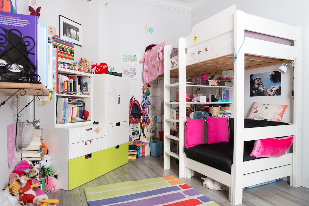 Dormitorio infantil con cama individual y cama plegable integrada en la gran silla negra.