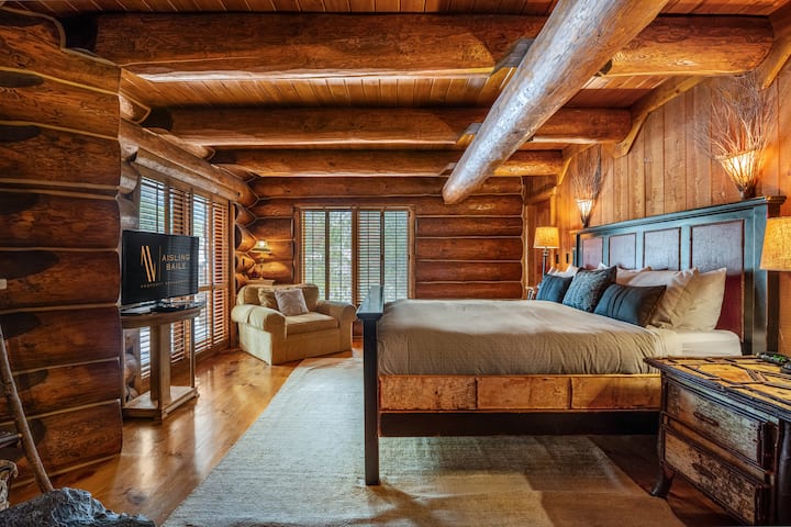 Chumba cha kulala cha msingi kwenye ghorofa kuu kilicho na kitanda cha kifalme, meko ya kuni, televisheni ya kebo, roshani ya kujitegemea na chumba kamili cha kuogea cha mvuke.