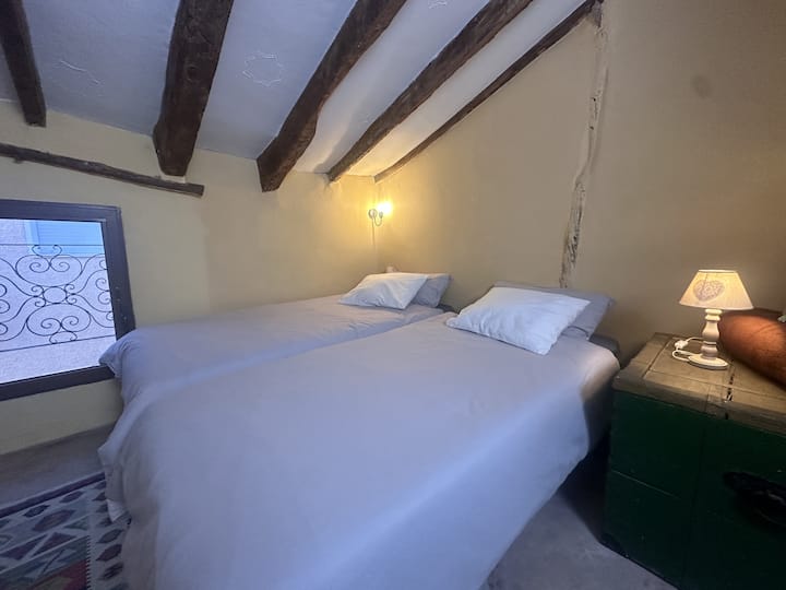 Dos camas individuales de 90cm con sofa a un lado y perchero para colgar la ropa así como una balda para guardar el equipaje