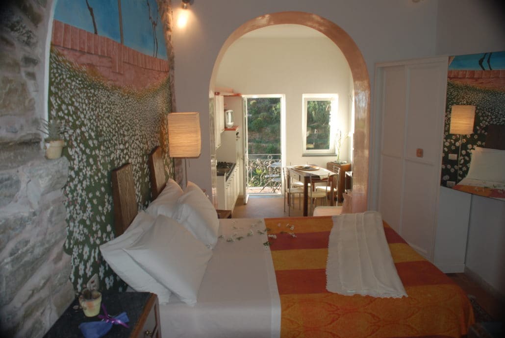 Overview of the double room, the open-plan equipped kitchen and the living area with balcony