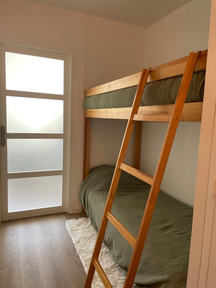 פינת ילדים בגומחה עם מיטות קומתיים מופרדות מהסלון על ידי דלת.