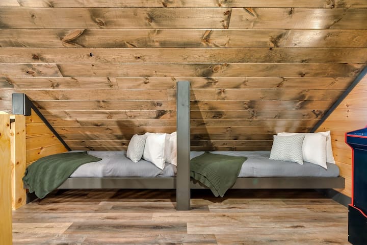 הלופט כולל שתי מיטות נפרדות לילדים, כל אחת עם מצעים, שמיכות טלאים נוחות ונוף של צמרות העצים דרך חלון, מה שהופך אותו למקום מסתור גחמני ונוח להרפתקאות קטנות