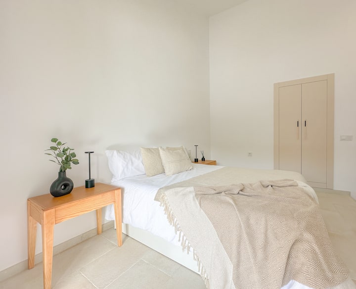 Ნათელი მთავარი საძინებელი ორადგილიანი საწოლით, ორი ღამის მაგიდით, სმარტ-ტელევიზორითა და დაცვის სექტორით.