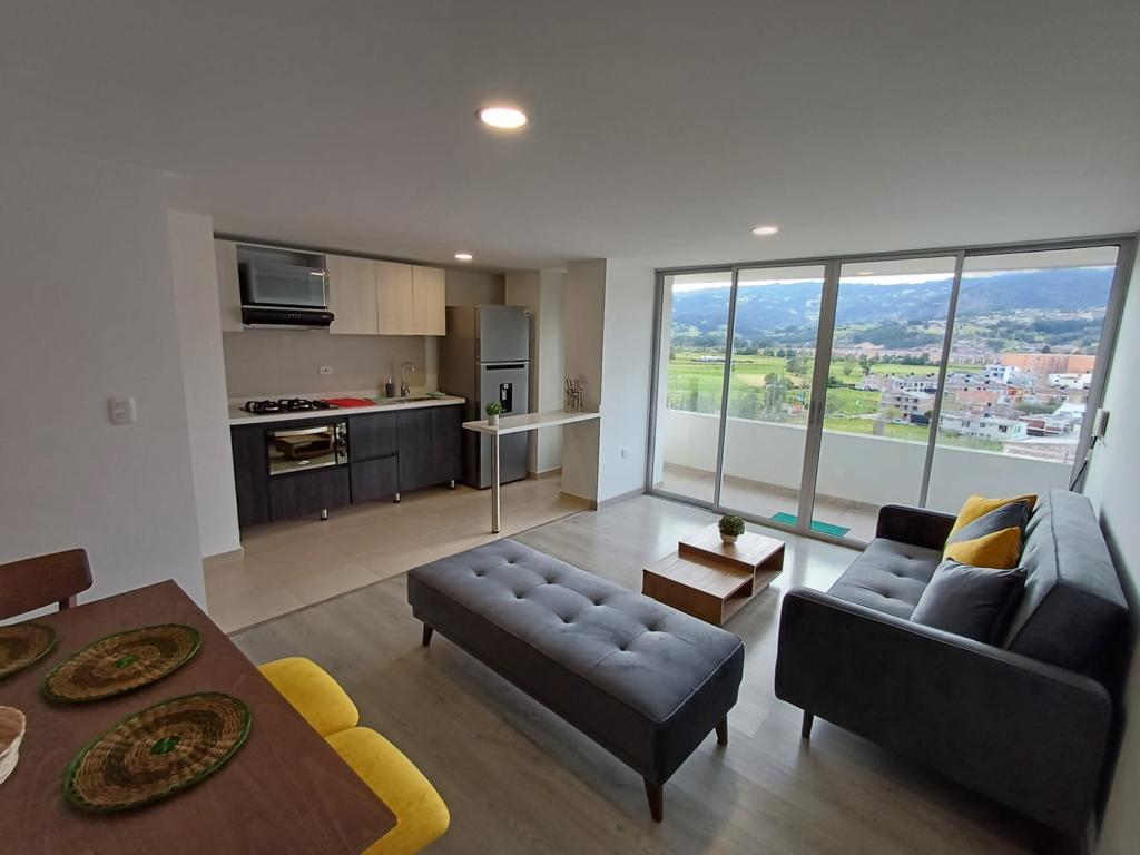 Дневна соба со француска врата се отвора кон балкон со поглед на градот и ридовите. Телевизор на ѕидот во дневната соба.