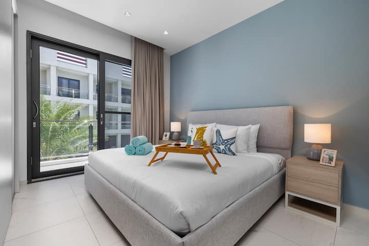 Dhomë gjumi elegante dhe elegante me mobilie të bardha dhe mure blu.