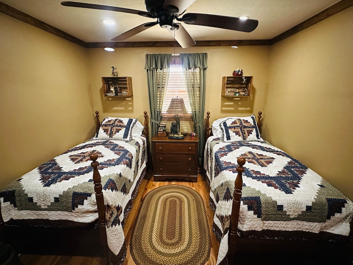 Dormitorio de invitados con dos camas individuales, ropa de cama nueva, armario, vestidor, televisor inteligente y mesa auxiliar.