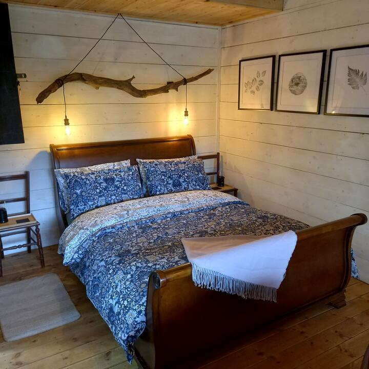 Uma cama king-size em forma de trenó; iluminação LED suspensa de madeira flutuante coletada; lanternas de cabeceira; e impressões de tinta feitas a partir da árvore da cabana e dos arredores da folhagem.