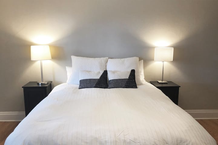 Spálňa 2: Veľké okná, pohodlná menšia manželská posteľ, napájanie na každej strane na nabíjanie telefónu, šatníková skriňa, sedacia stolička a stojan na batožinu, okenná klimatizačná jednotka počas letných mesiacov a prenosný ventilátor. 