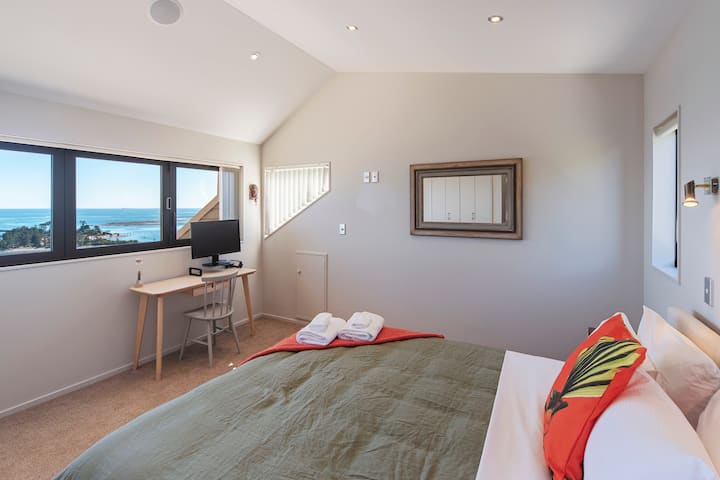 Dormitorio 1 (nivel superior): cama king con espacio de trabajo dedicado y vistas elevadas al mar y al jardín