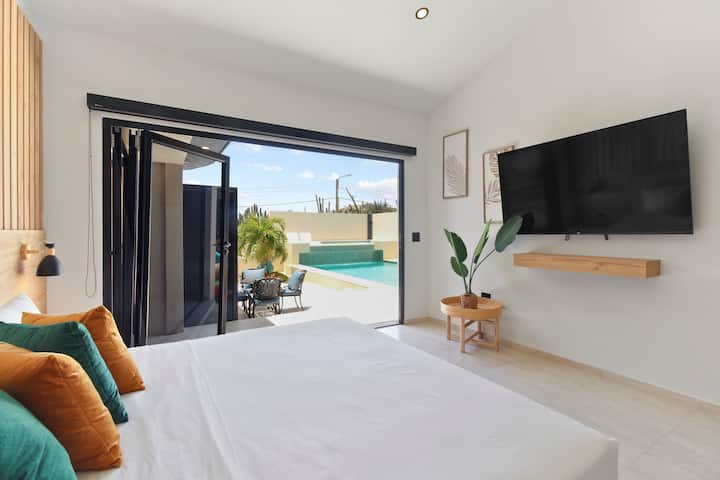 Dormitorio principal | Cuando estés listo para relajarte después de un emocionante día de exploración de Aruba, dirígete a esta lujosa cama tamaño king o sal y relájate alrededor del área de la piscina.