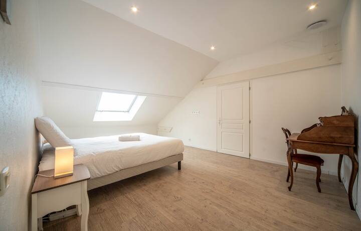 Amplia habitación de arriba con cama doble, sábanas suaves y espacio de trabajo