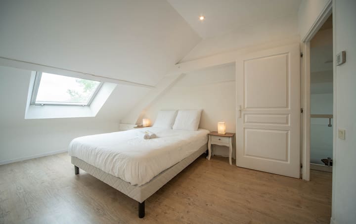 Amplia habitación de arriba con cama doble y sábanas suaves