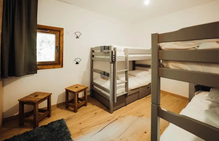 Cette chambre est située au RDC et permet à chaque enfant d'avoir son espace. De grands tiroirs sous les lits permettent de ranger les vêtements. Elément important: chaque lit a son bloc de recharge USB: les portables disent merci