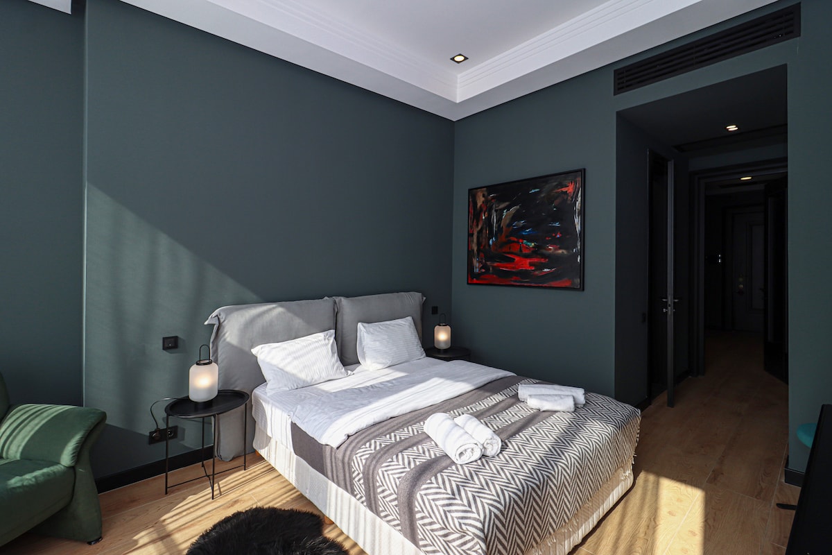 Este dormitorio cuenta con una cama doble con detalles verdes y arte en la pared, complementado con techos blancos.