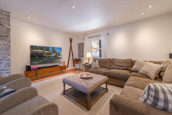 Уютна всекидневна с много кът за сядане, голям телевизор, Apple TV и др.