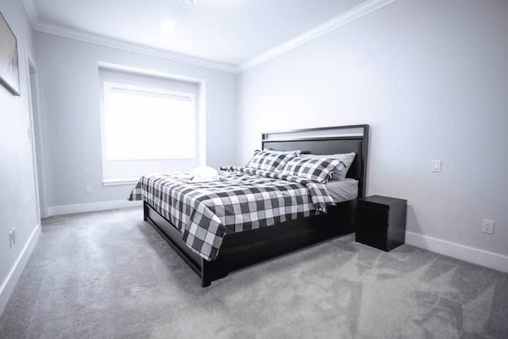 Treća spavaća soba mirno je utočište s bračnim krevetom, plišanom posteljinom, noćnim ormarićem i velikim prozorom za prirodno svjetlo.