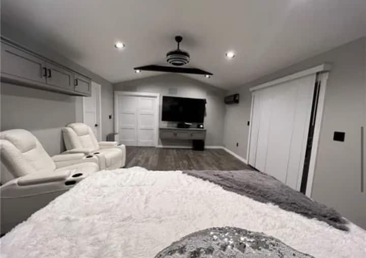 Primary bedroom with a king bed, TV and seating. An additional double-bed room is accessed through this bedroom, making the connected layout best for guests comfortable sharing access.
