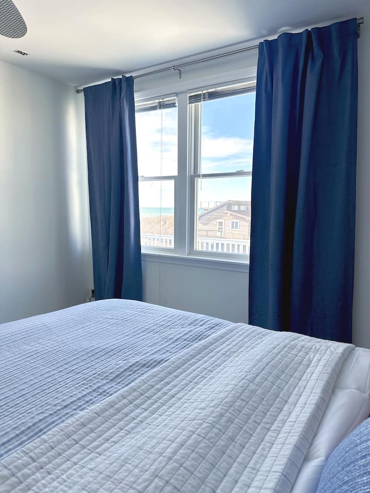 La chambre principale au deuxième niveau offre une vue sur l'océan depuis le lit king size. Un grand dressing avec commode et accès direct à la salle de bain du deuxième niveau.