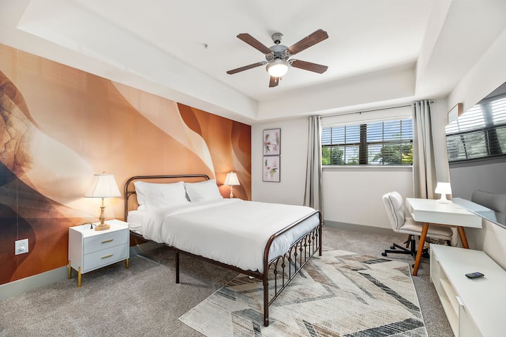 Cama queen junto con dos mesas de noche. También cuenta con un espacio de trabajo exclusivo y un televisor de 55 pulgadas