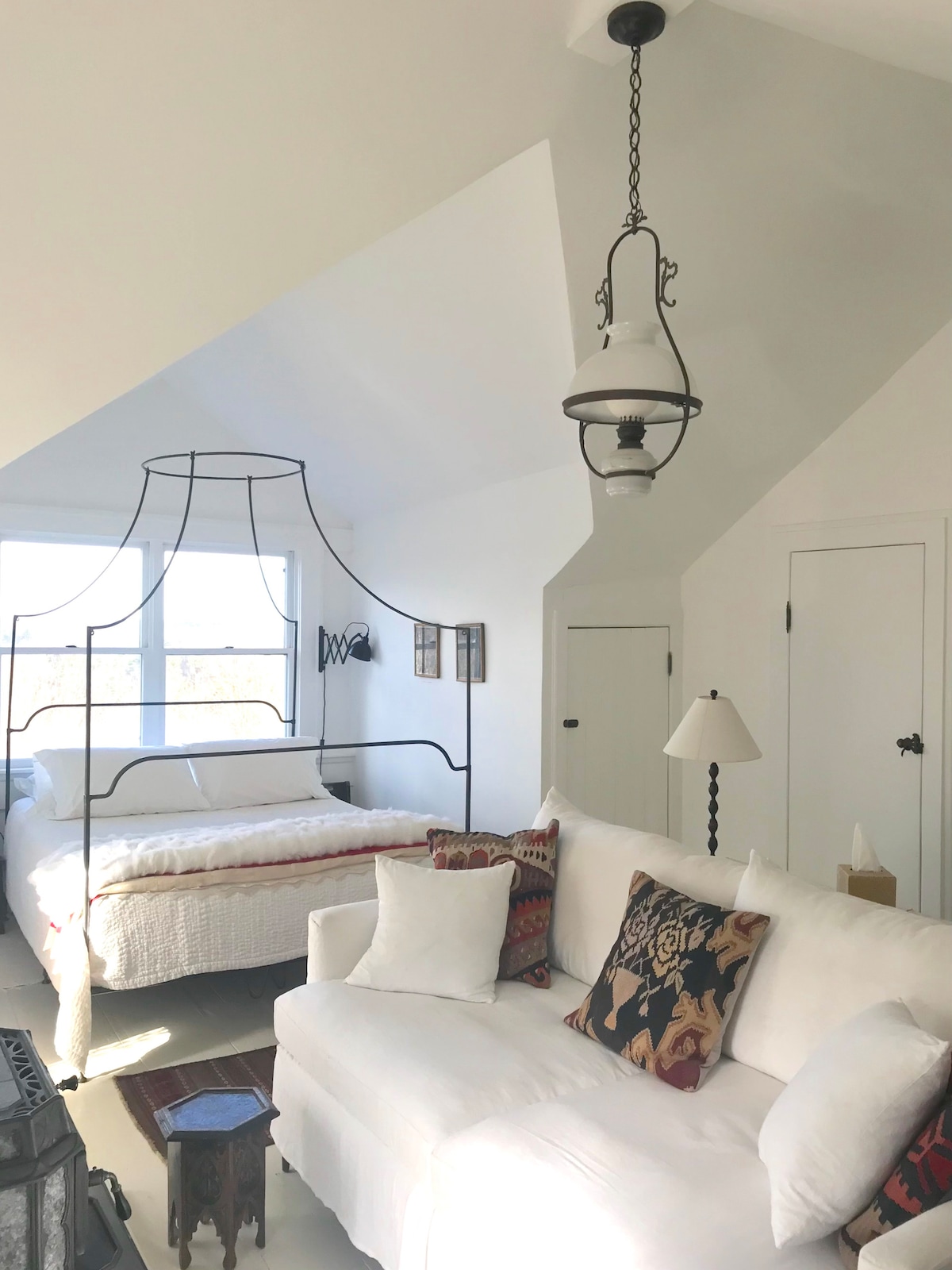 ספה עמוקה עם כריות מלאות וכיסוי מצעים אירי. מנורת שמן אופלין צרפתית עתיקה שהוסבה.