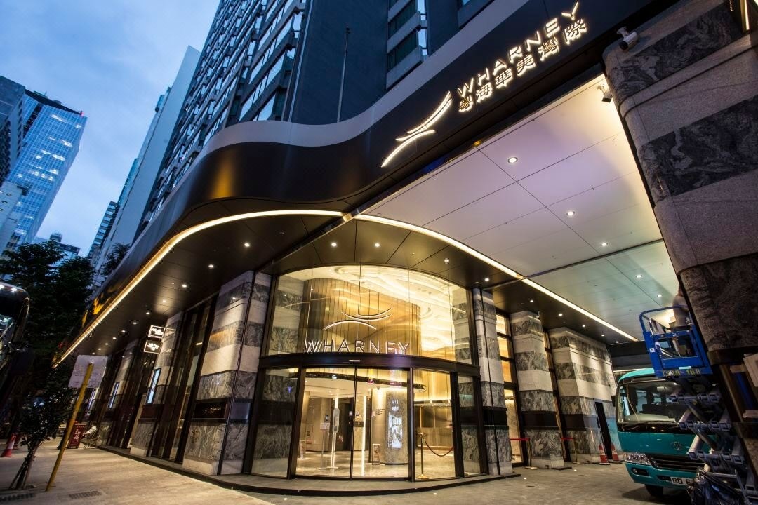 The welcoming entrance to the property features a sleek glass façade, enhanced by modern architectural lines. Well-lit signage identifies the location, while the expansive pathway leads to the main entrance, which is framed by stylish stone elements and is easily accessible.