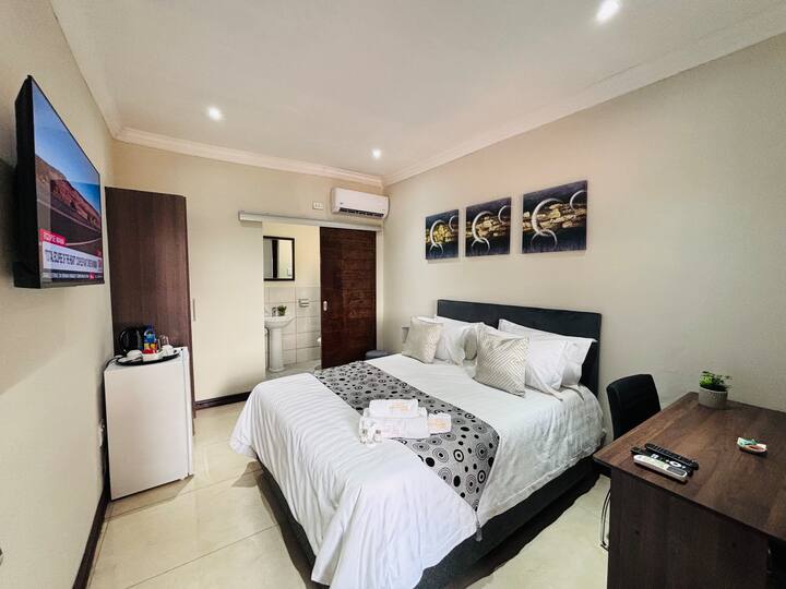 Karibu kwenye Chumba cha Vila 303, kinachopendwa na Mgeni kinachojulikana kwa mazingira yake tulivu na vistawishi vya uzingativu. Kamilisha na bafu lililokamilika kwa kioo. Pumzika kwenye kitanda cha malkia na mashuka meupe laini, yaliyozungukwa na kituo rahisi cha kazi na televisheni mahiri.