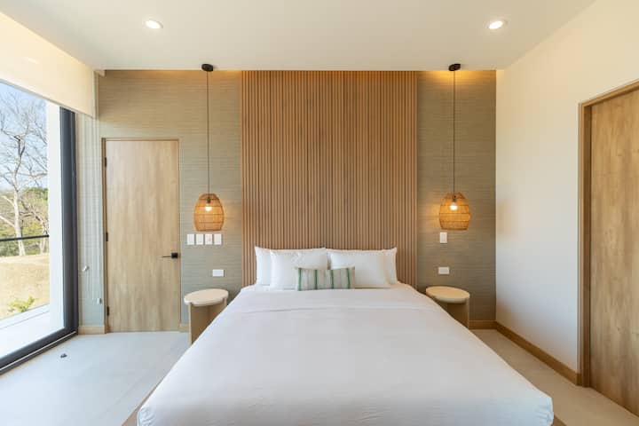 Relájate en el dormitorio principal del condominio Batimetria, Conviértete en Nosara, donde el lujo moderno y la comodidad crean un refugio perfecto