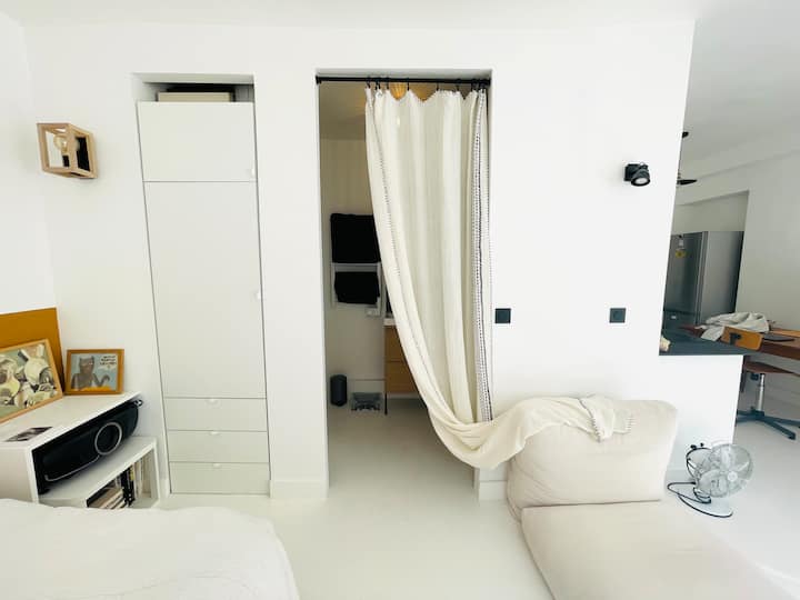 Badkamer aan de voet van het bed, gesloten door caravanslinnengordijn, met kledingkast ingebouwd in de muur. 