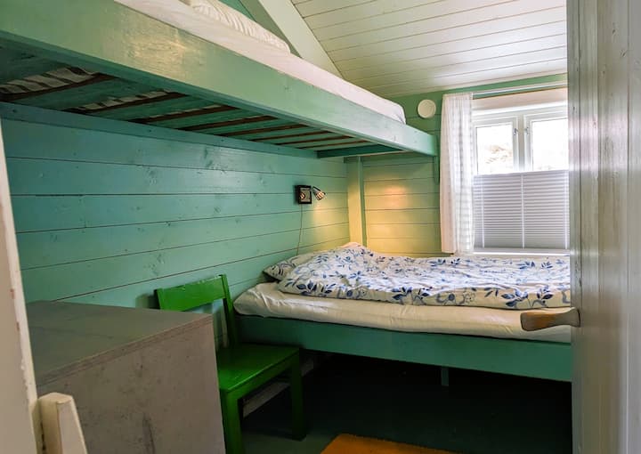 Das grüne Schlafzimmer verfügt über zwei geräumige Betten, 120 x 195 + 75 x 200 und ein Loft. Auf dem Boden im Loft befindet sich eine 90 cm breite Matratze, die als Bett genutzt werden kann. Im Raum gibt es auch eine Kommode.
Der Staubsauger befindet sich auf dem Boden unter dem Bett.