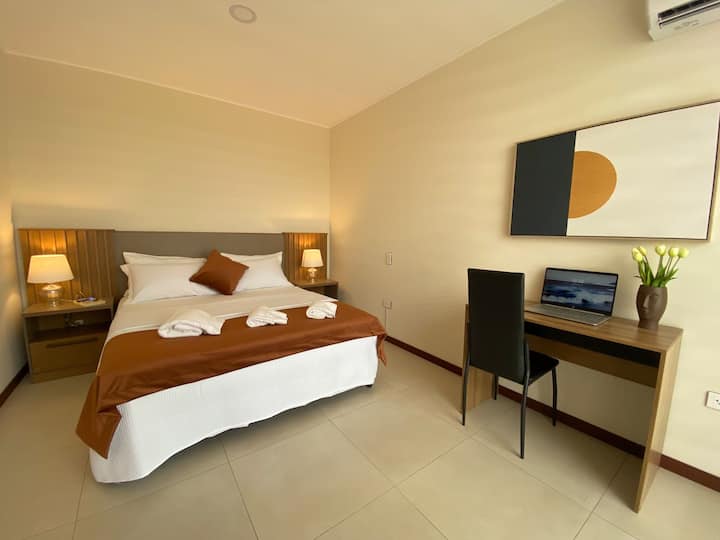 Dormitorio en suite con cama Queen, vestidor, balcón y área de trabajo.