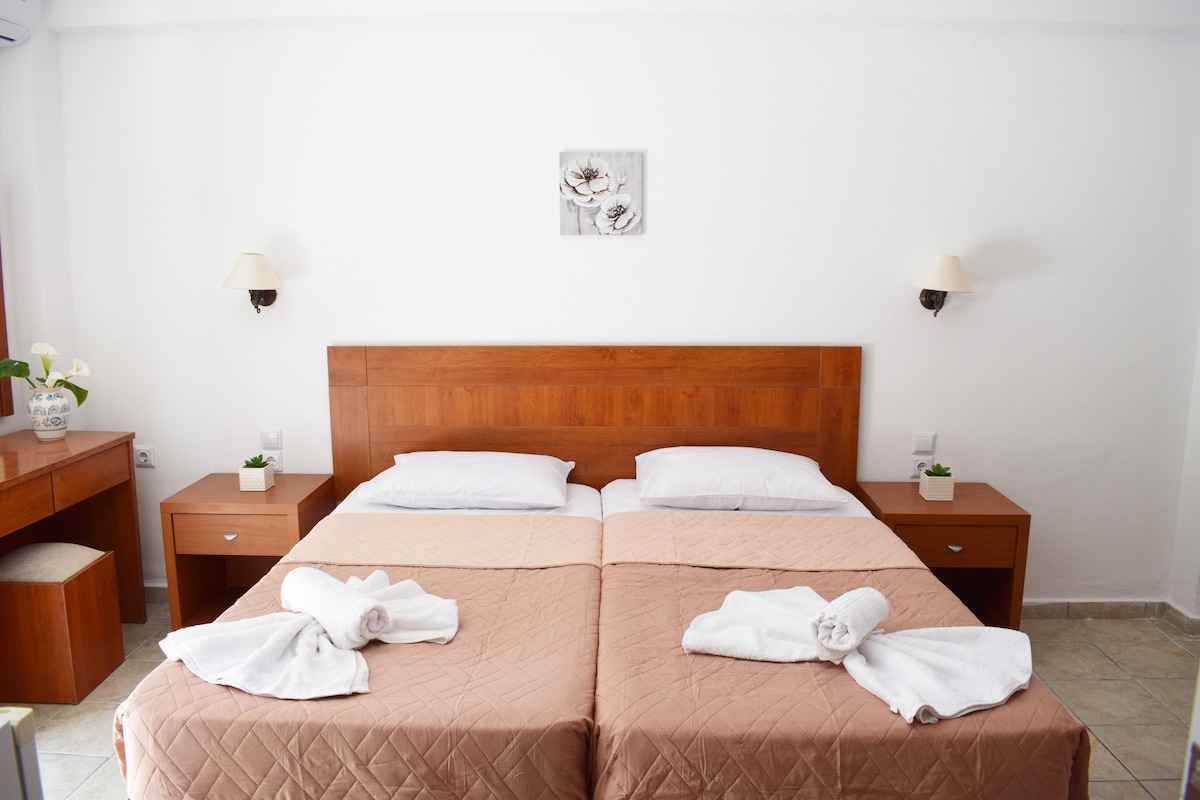 Საძინებელი გაყოფილი ორადგილიანი საწოლითა და საწოლთან მდგარი მაგიდებით