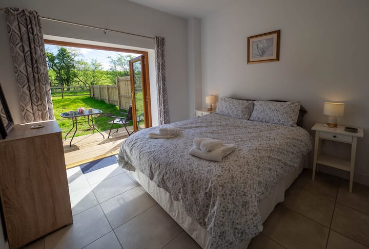 Spálňa na prízemí s priestrannou priestrannou posteľou a dverami na terasu, ktoré sa otvárajú na terasu. Cestovná detská postieľka k dispozícii.