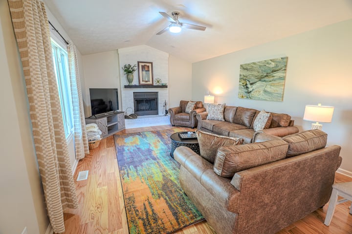 Sebule kuu yenye nafasi kubwa yenye kochi, kiti cha kupenda, kiti. Inajumuisha televisheni mahiri na eneo la moto la ndani. 