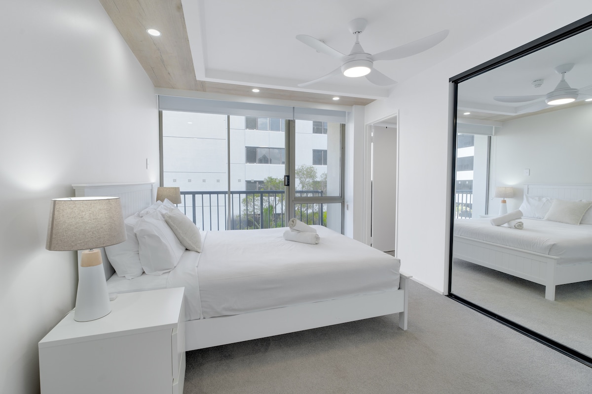 Ოთახი განათებულია ბუნებრივი სინათლით დიდი ფანჯრებიდან და აქვს თანამედროვე ჭერის ვენტილატორი კომფორტისთვის. Სარკისებური გარდერობი აუმჯობესებს სივრცეს, რბილი, ნეიტრალური ტონები კი მშვიდ, მშვიდ ატმოსფეროს ქმნის. 