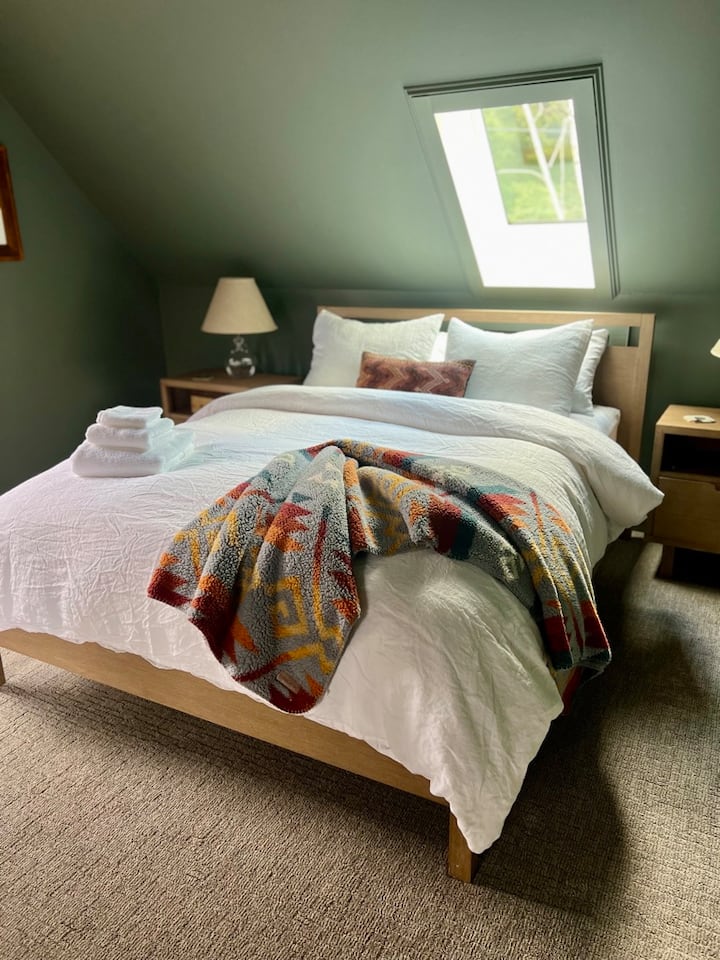 Пространа главна спална соба осветлена од сонцето со брачен кревет (широк 150-179 см), мека постелнина и простор наменет за работа — совршена за парови кои бараат удобност или работници на далечина кои сакаат да останат поврзани додека уживаат во мирно бегство од Вермонт.