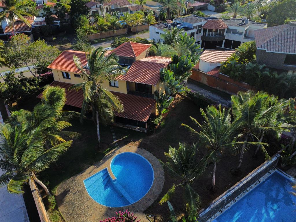 An aerial view captures a charming house surrounded by lush greenery and palm trees. A circular pool is visible, complemented by a stone patio. The well-maintained garden enhances the outdoor space, providing an inviting atmosphere for relaxation.